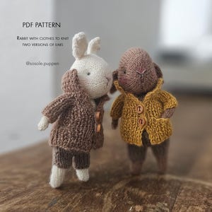 May include: Two knitted rabbit dolls with text reading PDF PATTERN RABBIT WITH CLOTHES TO KNIT TWO VERSIONS OF EARS @sosole.puppen. One white rabbit wears a brown knit cardigan and shorts, while the brown rabbit wears a yellow knit cardigan with buttons.