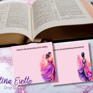 May include: Two pink cards featuring watercolour illustrations of women in gowns, with the text "A woman who walks with God will always reach her destination." The cards are in front of an open book.