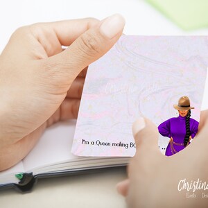 May include: A white notepad with a pink and gold marble design. The notepad has the text "I'm a Queen making BO..." written on it. A woman with long black braids is wearing a purple shirt, a brown hat, and a gold belt. The text "Christina Evette Events Design Gifts" is at the bottom of the notepad.