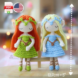 Peut inclure: Deux poupées crochetées à la main, l'une avec des cheveux roux et une robe verte, l'autre avec des cheveux blonds et une robe bleue. Chaque poupée mesure environ 12,7 cm de haut et a les yeux fermés. Les poupées sont ornées de bandeaux et sont posées sur une surface en bois.