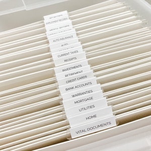 May include: A white file organizer with labeled tabs for different categories of documents, including employment records, medical records, auto insurance, current taxes, receipts, investments, retirement, credit cards, bank accounts, warranties, mortgage, utilities, home, and vital documents.