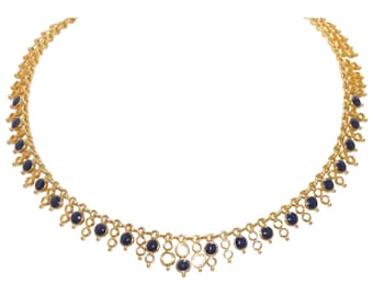 May include: A gold-toned necklace with a delicate chain design. The necklace features small, round, dark blue gemstones and open circle accents. The gemstones are evenly spaced along the lower portion of the necklace, creating a symmetrical pattern.