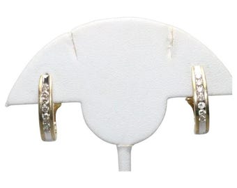 May include: A pair of hoop earrings crafted from two-tone gold, featuring a channel setting with a row of small, clear, round-cut stones embedded along the front surface of each earring, showcasing a polished metallic finish and a secure hinged closure.
