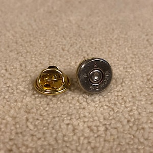 Peut inclure: Deux petites épingles rondes en métal. Une épingle est dorée et l'autre est argentée. L'épingle argentée porte l'inscription "Winchester" et "30-30".