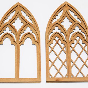 May include: Two wooden arched window frames with intricate cutouts. The frame on the left has a simple design, while the frame on the right has a diamond pattern.