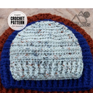 May include: A close-up of a crocheted beanie hat in a light gray color with brown and blue flecks. The hat is layered on top of two other crocheted hats, one in blue and one in brown.