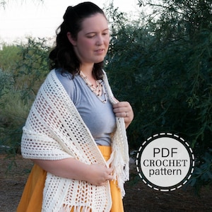 May include: A white crochet shawl with fringe, worn by a person with a gray shirt and a yellow skirt. The image includes the text "PDF CROCHET pattern".