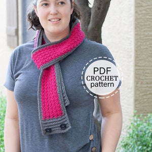 May include: A woman wearing a gray shirt and a pink and gray crocheted scarf with buttons. The scarf is a crochet pattern that is available as a PDF download.