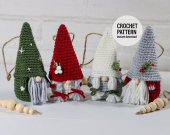 May include: Four crocheted gnome ornaments with different colored hats: green, red, white, and gray. Each gnome has a white beard and a small sprig of greenery. The ornaments are hanging from a string with wooden beads. The text "CROCHET PATTERN instant download" is visible in the image.