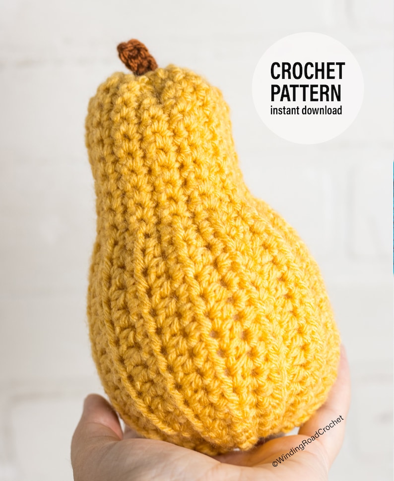 Puede incluir: Una pera de crochet de color amarillo, sostenida en una mano. La pera tiene un tallo marr&oacute;n. El texto "CROCHET PATTERN instant download" es visible en la imagen.