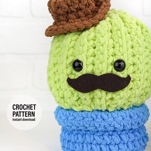 May include: Crochet pattern for a green cactus wearing a brown cowboy hat and a black mustache. The cactus is sitting on a blue base. The pattern is available for instant download. The image also includes the text "CROCHET PATTERN instant download".