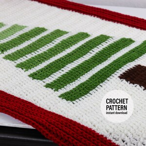 Może przedstawiać: Biały bieżnik na stół wykonany na szydełku z wzorem zielono-białego, paskowanego drzewka choinkowego i brązowym pniem. Bieżnik ma czerwoną obwódkę. Tekst "CROCHET PATTERN instant download" znajduje się na białym kółku.