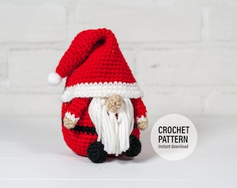 May include: Crocheted Christmas gnome with a red hat, white beard, and black boots. The gnome is sitting on a white surface. The text "CROCHET PATTERN instant download" is visible in the image.