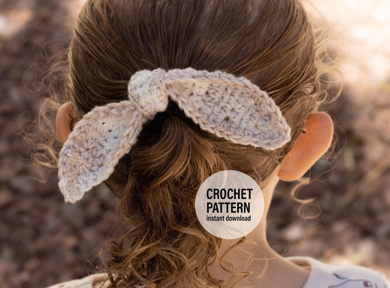 May include: A crocheted hair tie in a light beige color, tied in a bow, in a girl's hair. The text "CROCHET PATTERN instant download" is on a white circle.