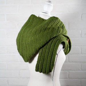 May include: A green crocheted cowl with a long, flowing end. The cowl is draped over a white mannequin.
