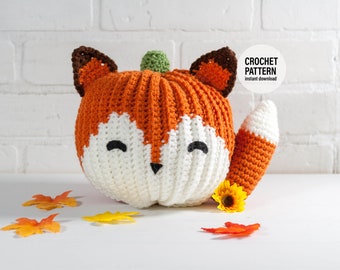 May include: Crochet pattern for a pumpkin-shaped fox amigurumi toy. The toy is orange and white with a brown nose and green stem. The pattern is available for instant download.