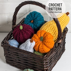 Puede incluir: Una cesta de mimbre llena de calabazas y calabacines tejidos a crochet en varios colores, incluyendo naranja, amarillo, turquesa, burdeos y gris. La cesta est&aacute; sobre una superficie blanca. El texto "CROCHET PATTERN instant download" es visible en la esquina superior derecha de la imagen.