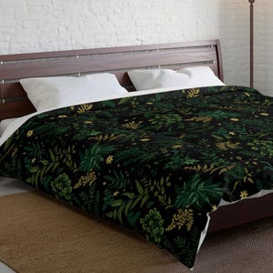 May include: A black duvet cover with a green and gold floral pattern. The duvet cover is on a bed with white pillows and a brown wooden headboard. The bed is in a bedroom with a white brick wall, a brown rug, and a lamp.
