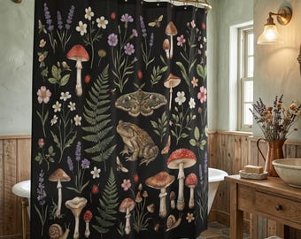 May include: A black shower curtain featuring a botanical print of various mushrooms, ferns, lavender, wildflowers, a large moth, a toad, and snails. The design is arranged in a repeating pattern across the fabric, hanging from a metal rod.