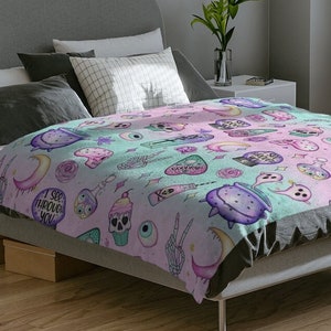 May include: A pastel pink and green bedspread with a whimsical pattern of moons, stars, skulls, eyes, and other spooky and cute designs. The text "I see through you" is featured on the bedspread.