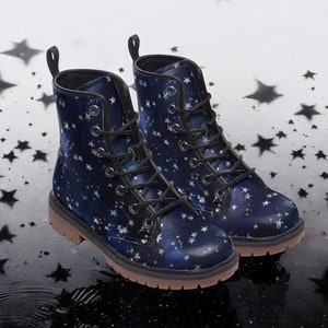 Könnte beinhalten: Ein Paar dunkelblaue Stiefeletten mit einem weißen Sternenmuster. Die Stiefel haben schwarze Schnürsenkel und eine braune Sohle.