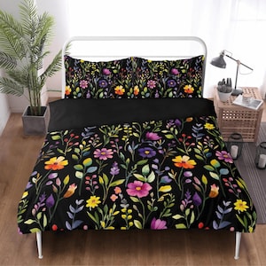 May include: A floral duvet cover set with a black background. The bedding features a colorful pattern of flowers and foliage in shades of yellow, orange, purple, and pink. The set includes a duvet cover and two pillowcases, creating a vibrant bedroom aesthetic.
