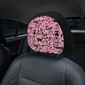 May include: Pink and black car headrest cover with a Halloween themed pattern. The pattern includes ghosts, cats, witches' hats, and other spooky symbols.