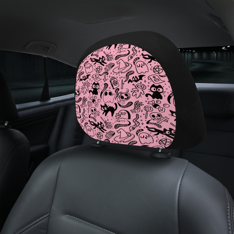 May include: Pink and black car headrest cover with a Halloween themed pattern. The pattern includes ghosts, cats, witches' hats, and other spooky symbols.