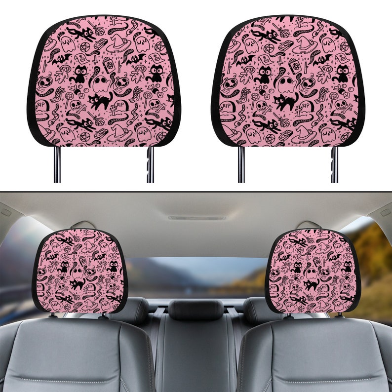 May include: Two pink car headrest covers with a black and white spooky Halloween pattern featuring ghosts, cats, bats, and witch hats.