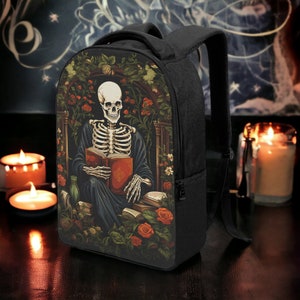 Puede incluir: Mochila negra con un esqueleto leyendo un libro en un jard&iacute;n. El esqueleto lleva una t&uacute;nica azul y est&aacute; rodeado de flores y libros.