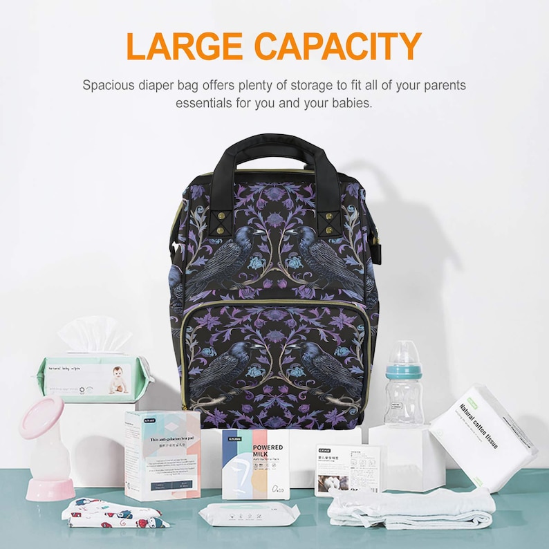 May include: A black diaper bag with a floral and bird print. The bag has a large capacity and is perfect for carrying all of your baby's essentials. The bag is sitting on a table with other baby items, including wipes, bottles, and breast pump supplies.
