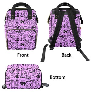 May include: A purple backpack with a black and white print of ghosts, cats, and other spooky Halloween imagery. The backpack has adjustable straps and a zippered front pocket.