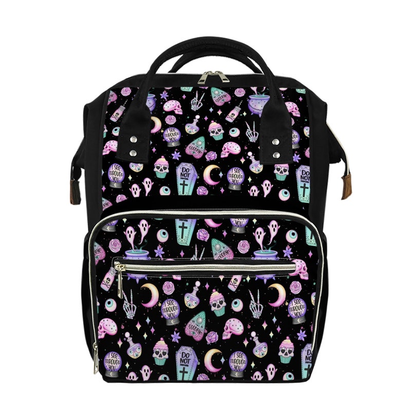 May include: A black canvas diaper bag with a whimsical pattern featuring skulls, ghosts, potion bottles, cupcakes, and the text "I see through you" and "Do not disturb".