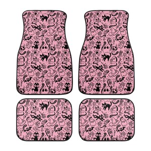 May include: Set of four pink car floor mats with a black and white Halloween themed pattern. The pattern includes ghosts, bats, cats, skulls, and other spooky elements.