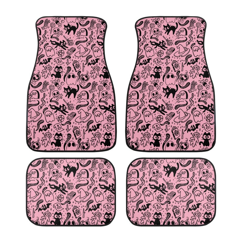 May include: Set of four pink car floor mats with a black and white Halloween themed pattern. The pattern includes ghosts, bats, cats, skulls, and other spooky elements.