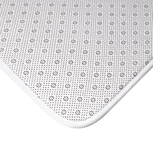 May include: Close-up of the underside of a white bath mat with a black patterned non-slip backing.