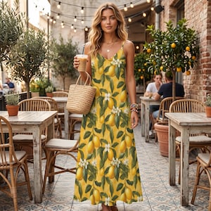 May include: A yellow sundress with a lemon and floral print. The dress has spaghetti straps and a V-neck. A straw tote bag and a beverage are held in the hand. The background includes outdoor cafe tables and string lights.