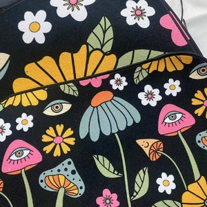Puede incluir: Alfombra psicod&eacute;lica en blanco y negro con un dise&ntilde;o floral y de hongos. La alfombra presenta flores amarillas, rosas, azules y verdes, as&iacute; como hongos con ojos.