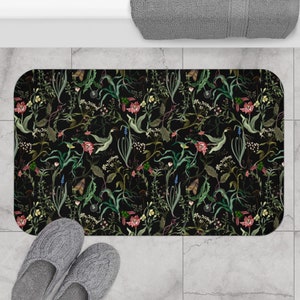 May include: Black bath mat with a floral pattern featuring various flowers and leaves in shades of green, pink, and yellow.