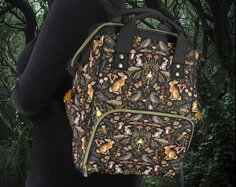May include: A black backpack with a woodland-themed print featuring rabbits, birds, and mushrooms. The backpack has a large main compartment and a smaller front pocket.