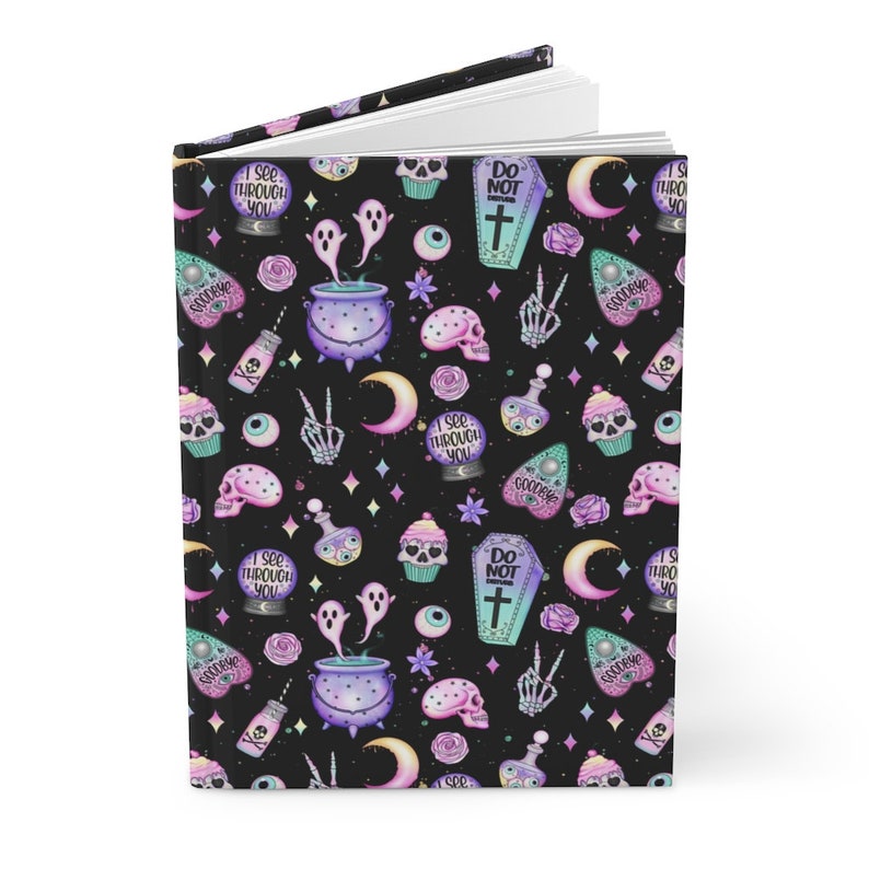 K&ouml;nnte beinhalten: Ein schwarzes Journal mit einem gruseligen, pastell-gotischen Muster. Das Muster enth&auml;lt Geister, Sch&auml;del, Aug&auml;pfel, Cupcakes, Zaubertrankflaschen, Herzen und einen zunehmenden Mond. Der Text auf dem Journal lautet "Ich sehe durch dich" und "Betreten verboten".