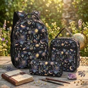 Op de afbeelding: Een zwarte rugzak, een lunchtas en een etui, allemaal met een hemels patroon van gele zonnen, maansikkels en kleurrijke bloemen. De set bevat een notitieboek met een bruine kaft en twee donkere houten pennen op een houten ondergrond.