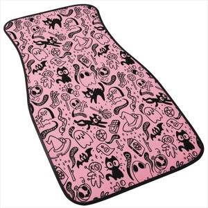 May include: Pink car floor mat with a black and white Halloween themed pattern. The pattern includes ghosts, cats, bats, skulls, and other spooky symbols. The text "GRRAAAHH" and "RIP" are repeated throughout the pattern.