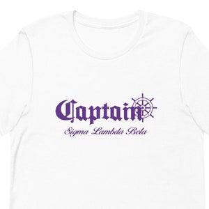 Könnte beinhalten: Weißes T-Shirt mit einer lilafarbenen Grafik eines Schiffsrades und dem Text "Captain Sigma Lambda Beta".