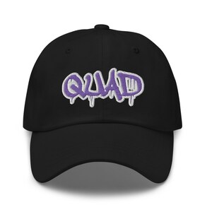 May include: Black baseball cap with a purple and white embroidered "QUAD" graphic.