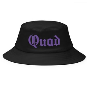 Könnte beinhalten: Schwarzer Bucket Hat mit einem lila "Quad" auf der Vorderseite gestickt.