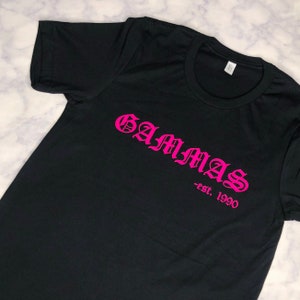 May include: Black t-shirt with a pink graphic that says "GAMMAS -est. 1990"