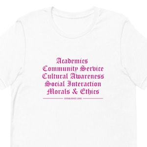 May include: White t-shirt with a pink text design that reads "Academics, Community Service, Cultural Awareness, Social Interaction, Morals & Ethics, Established 1990".