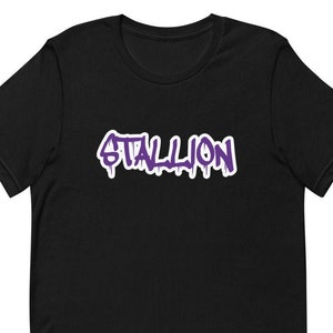 Könnte beinhalten: Schwarzes T-Shirt mit einem violetten "STALLION"-Motiv im Graffiti-Stil.