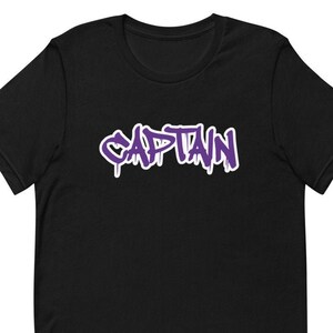 Könnte beinhalten: Schwarzes T-Shirt mit einem violetten "CAPTAIN"-Motiv im Graffiti-Stil.